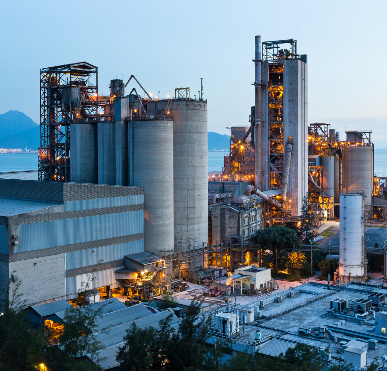 Industrial facility with large towers, lit up at dusk