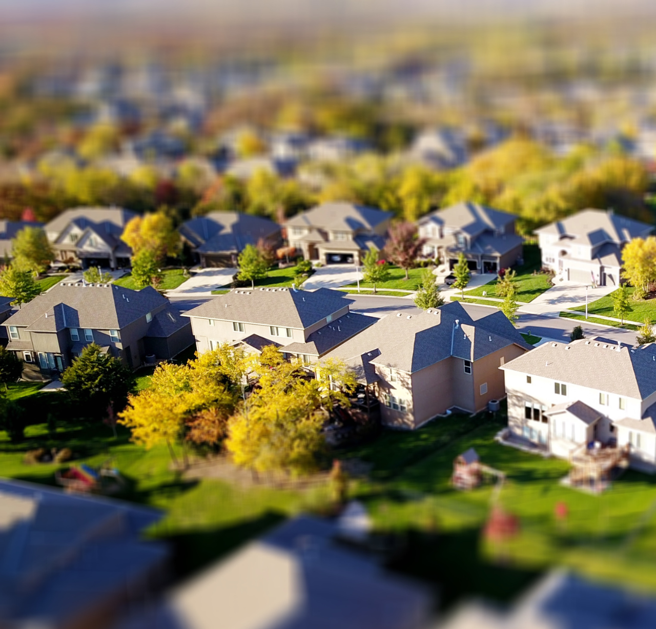 An above photo of houses in a neighborhood street with trees surrounding them